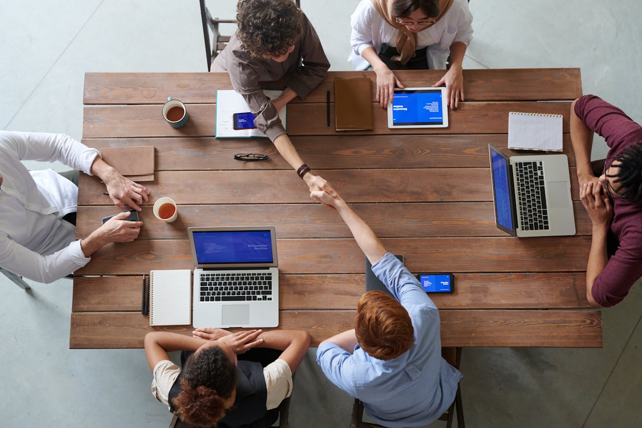 Services Overhead view of colleagues in a work meeting using laptops and tablets, emphasizing teamwork and technology.