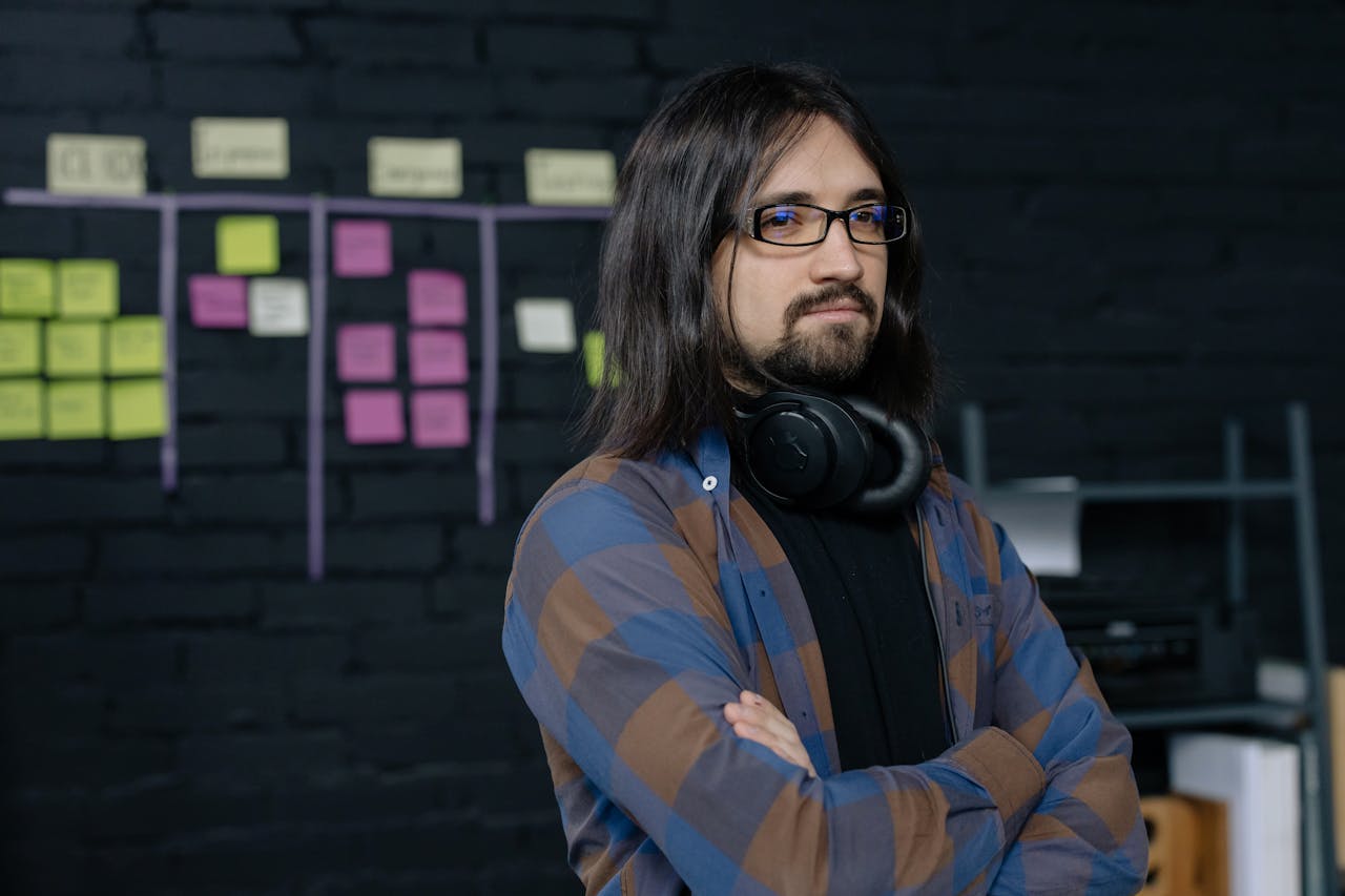 Home Portrait of a confident IT professional with headphones, standing in a modern office with sticky notes.