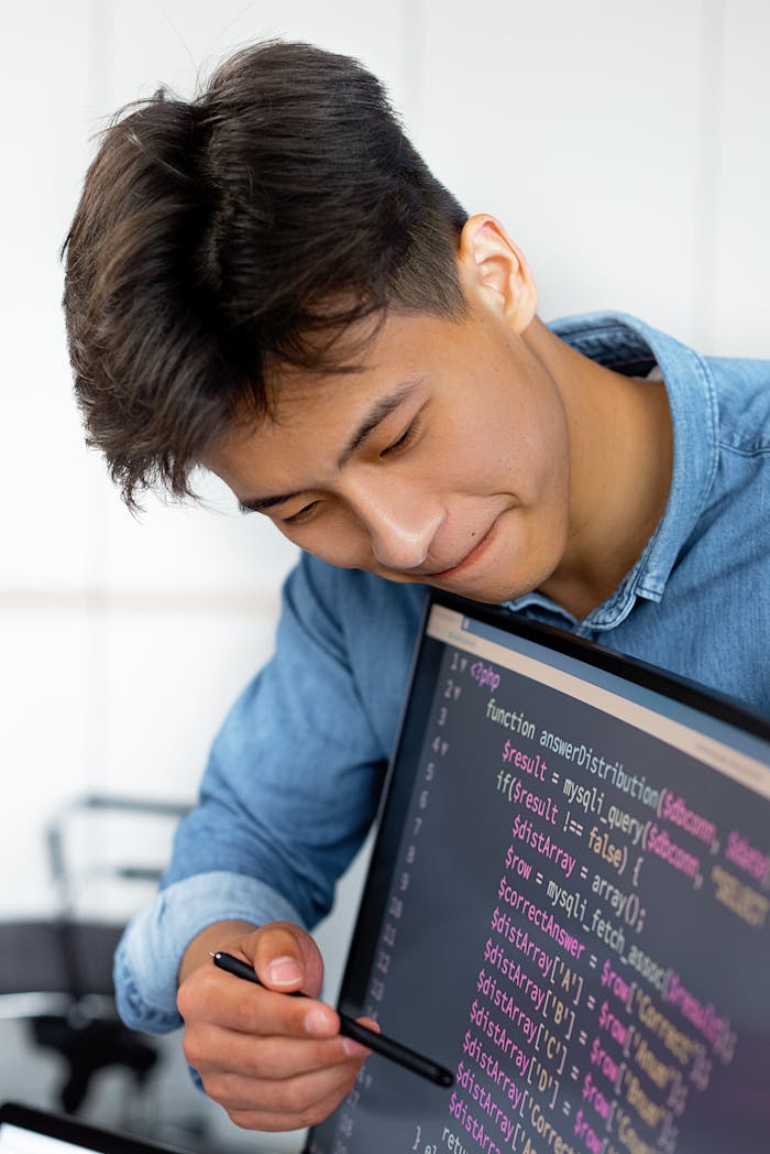 Services A young man smiles while programming in a modern office environment.